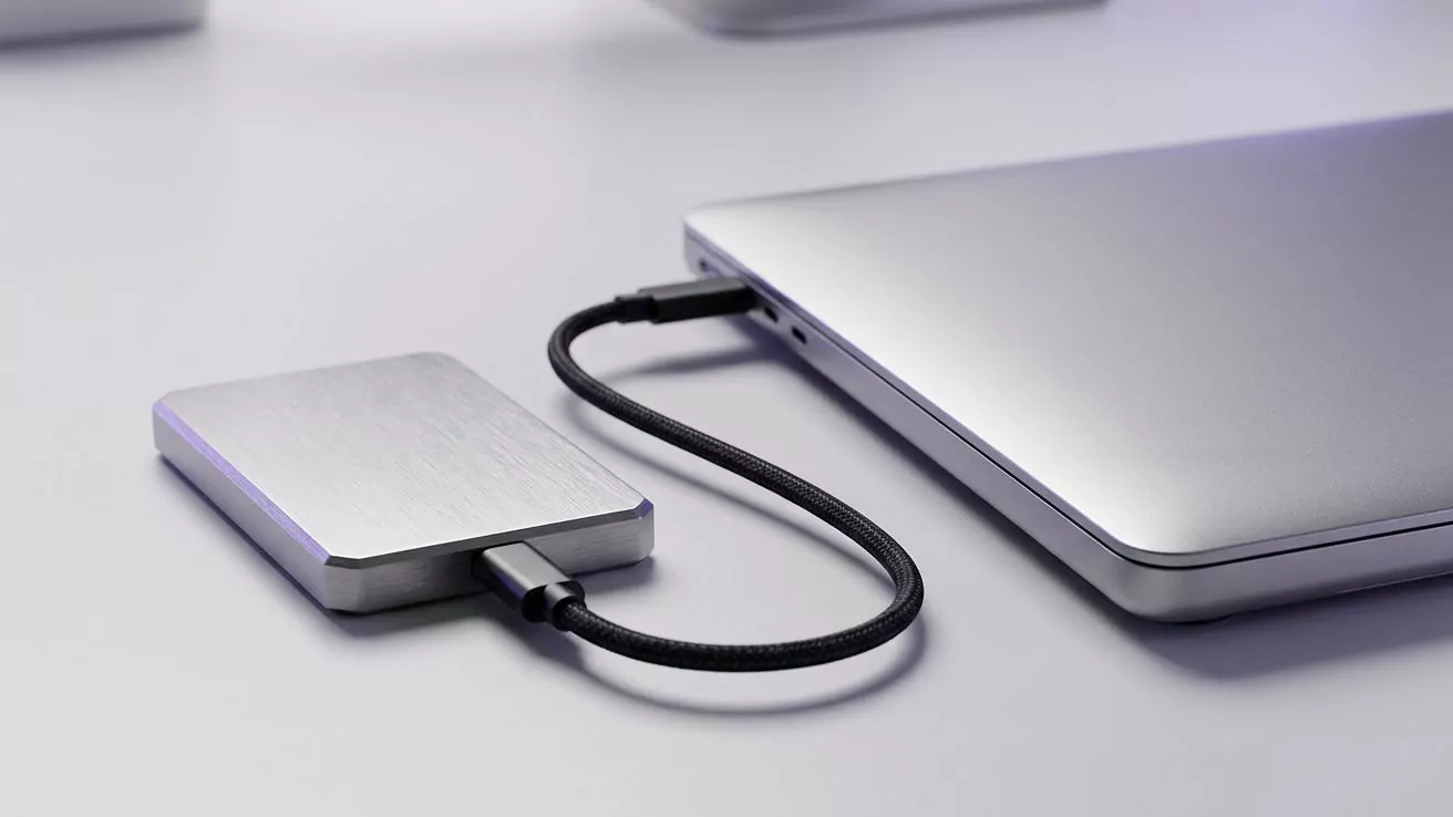 External drive cabled to a closed laptop, standing for backing up the ~/.codex folder before you delete it