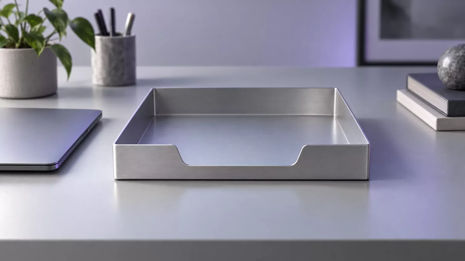 Empty aluminium desk tray next to a closed laptop, standing for the disk space freed after removing Parallels